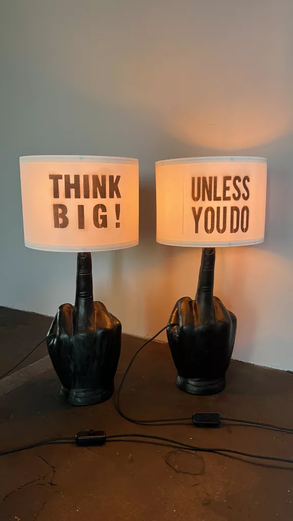 Mut & Mittel eingeschaltet: zwei Handsockel mit den Schirmen THINK BIG! und UNLESS YOU DO