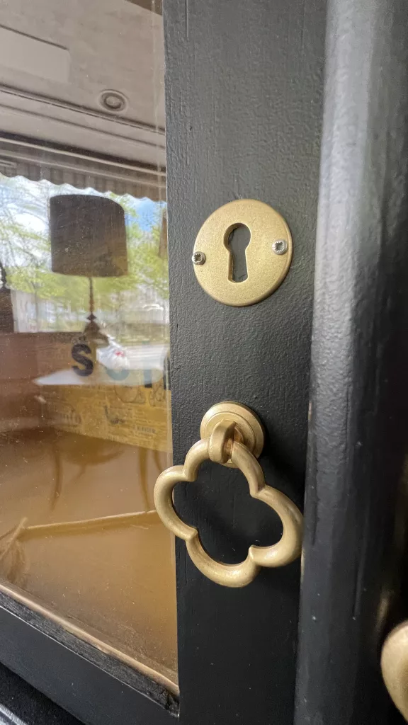 Detail an Schnappslotte: goldener Schlüsselbeschlag auf dunkler Tür