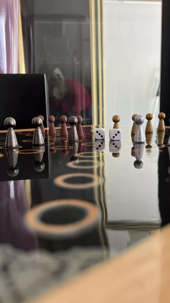 Detail der Spielfläche: Figuren und Würfel spiegeln sich im Epoxidharz