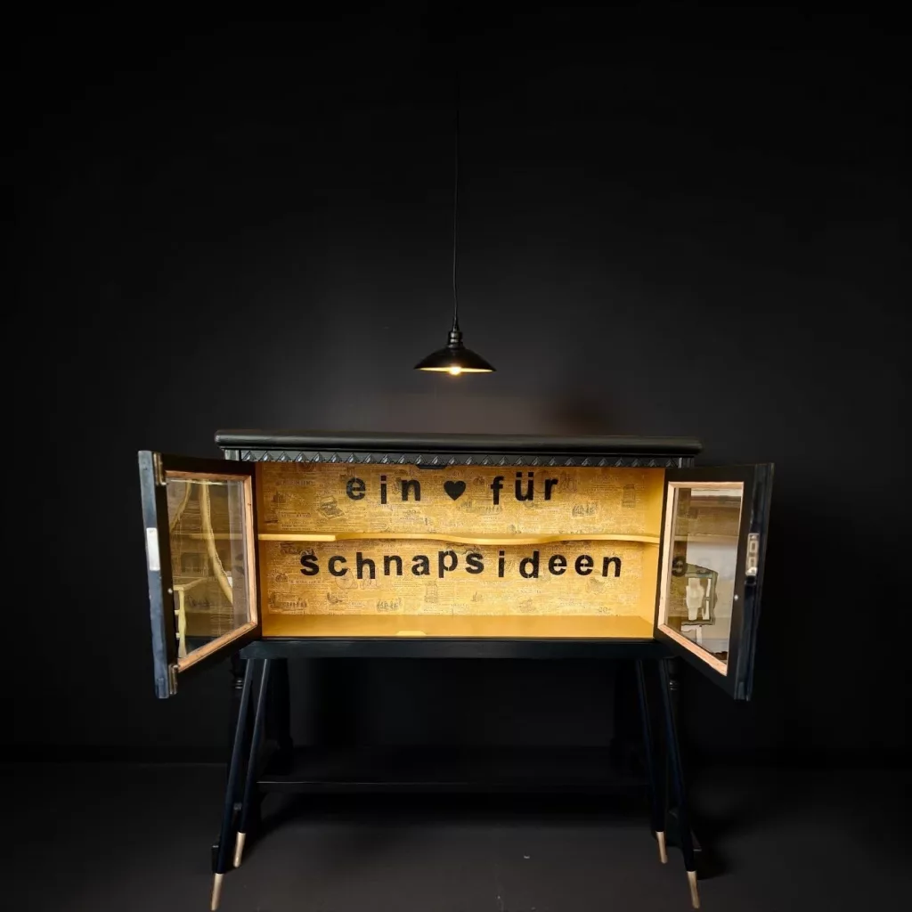 Schnappslotte im Dunkeln mit geöffneten Türen, Schriftzug ein Herz für Schnapsideen
