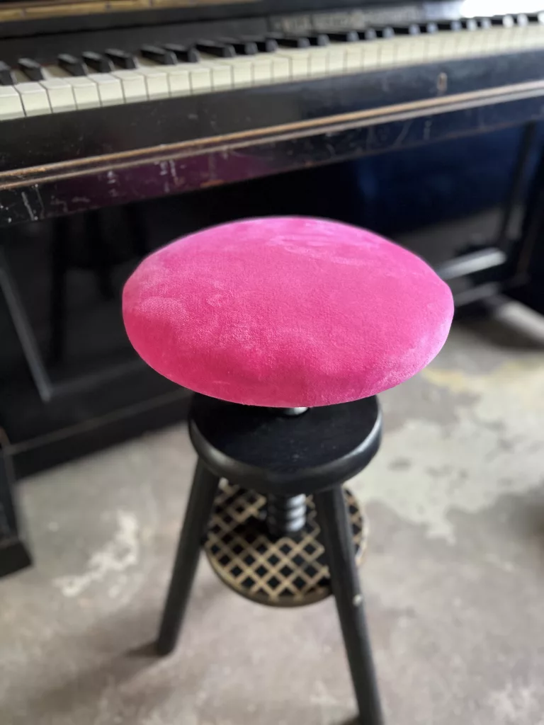 Polly vor einem Klavier: höhenverstellbarer Hocker mit pinkfarbenem Rundsitz