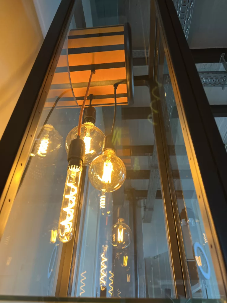 Blick durch Sentas Glasfront auf die Kette warm leuchtender Glühbirnen
