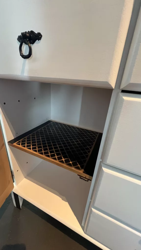 Blick in Lisas geöffnetes Fach mit schwarzem Gitterboden und Ringgriff