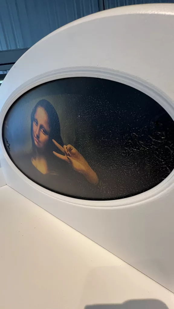 Nahaufnahme des Mona-Lisa-Motivs im ovalen Aufsatz von Lisa, Selfie-Pose