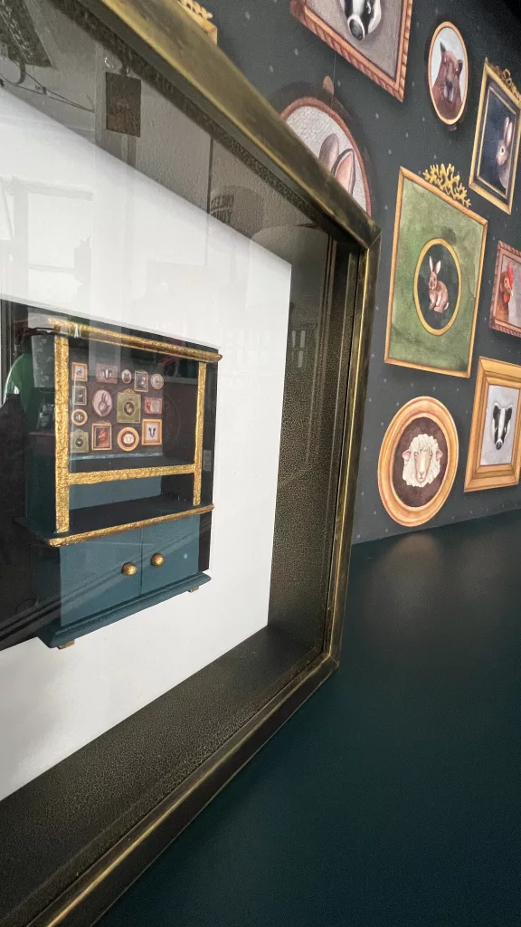 Blick von der Seite in die Vitrine, die Tierporträts auf der Rückwand