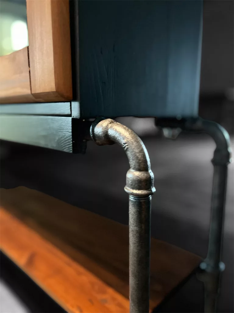 Detail an Bernd: Bein aus altem Wasserrohr mit Rohrbogen, daneben die Holzablage