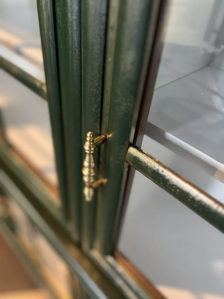 Detail an Theodor: goldfarbener Griff auf grüner Sprossentür
