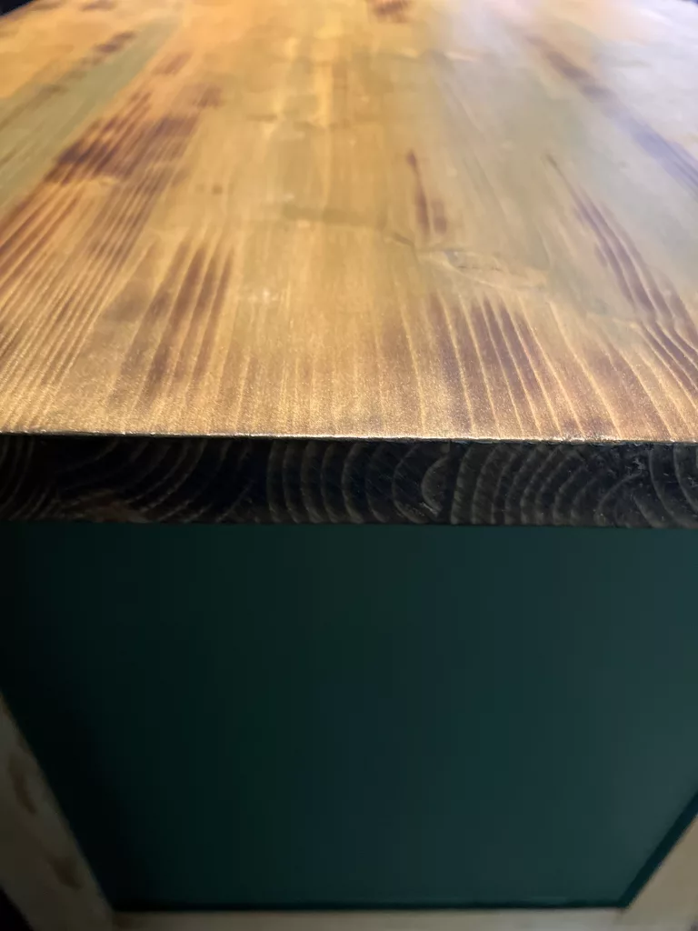 Die Kante der Holzplatte über dem grünen Korpus