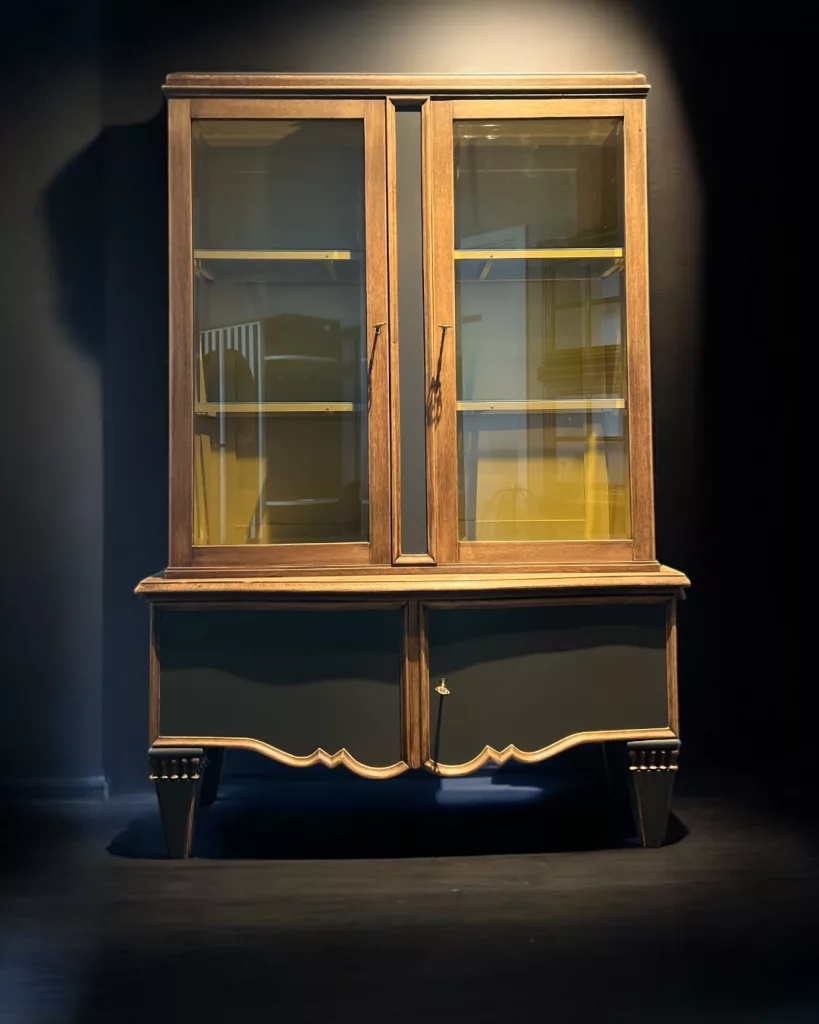 Holz Hubert frontal: Vitrine mit hellem Holzrahmen und currygelbem Innenleben