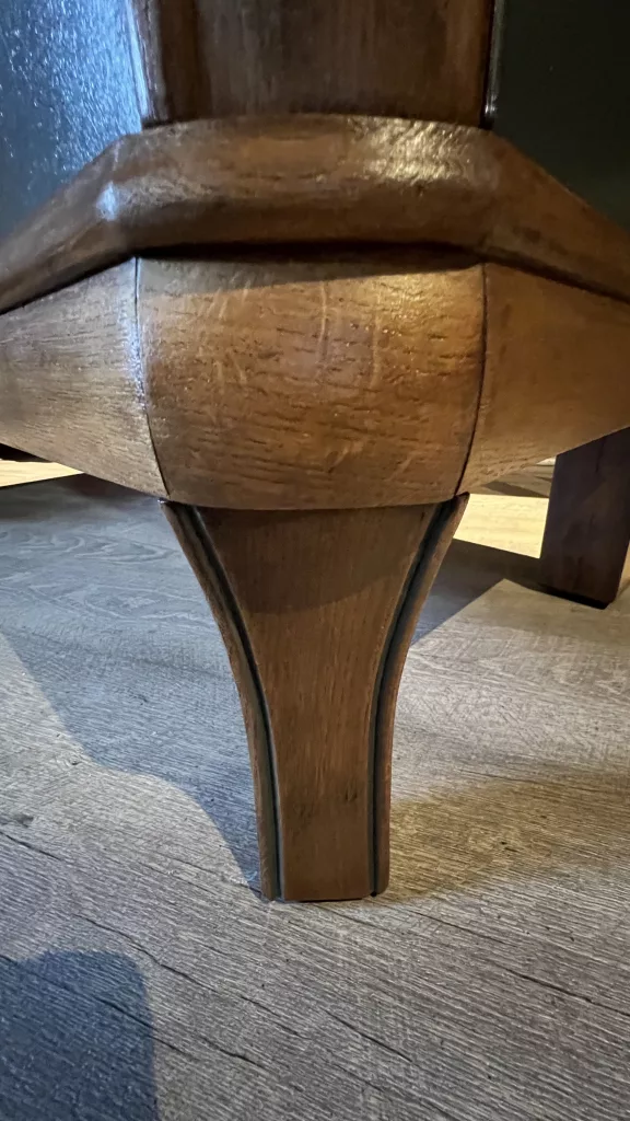 Detail eines geschwungenen Holzbeins unter dem Korpus