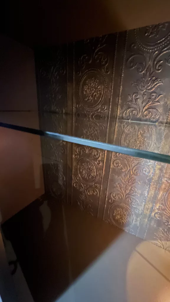 Detail von Ursulas Innenwand mit geprägter Tapete und Glasboden