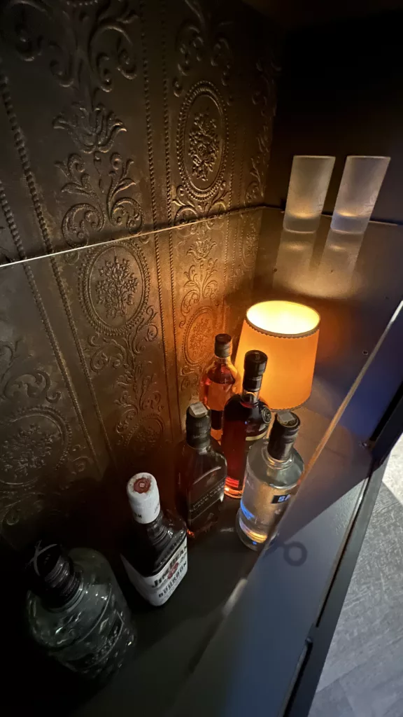 Die Hausbar von innen, Lampe und Flaschen vor der Prägetapete