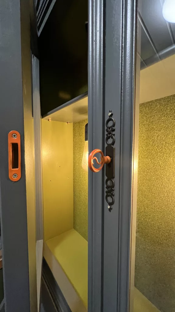 Blick zwischen die Glastüren auf die gelb leuchtende Rückwand