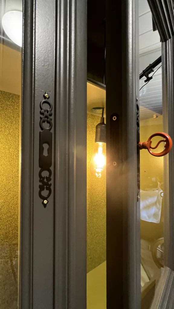 Zierbeschlag und Glühbirne hinter dem Glas