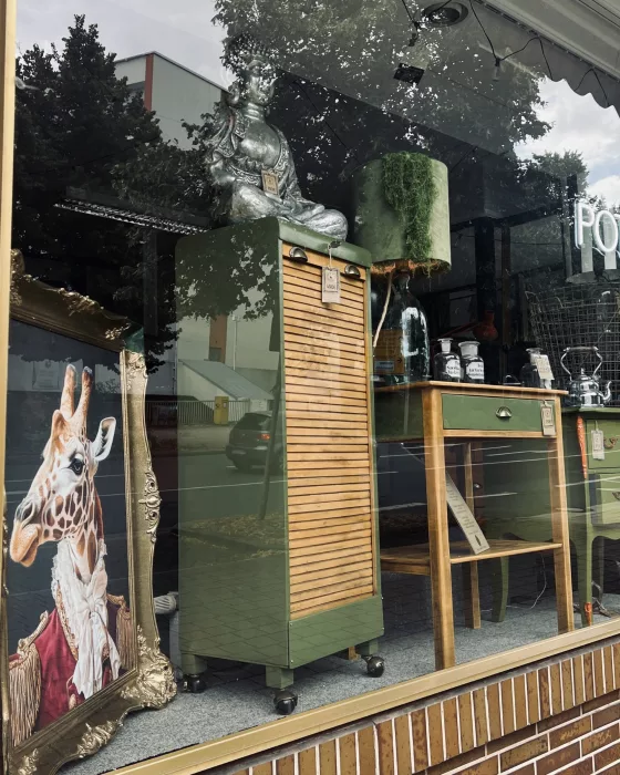 Schaufenster von außen mit Kunstdruck und grüner Vintage-Kommode